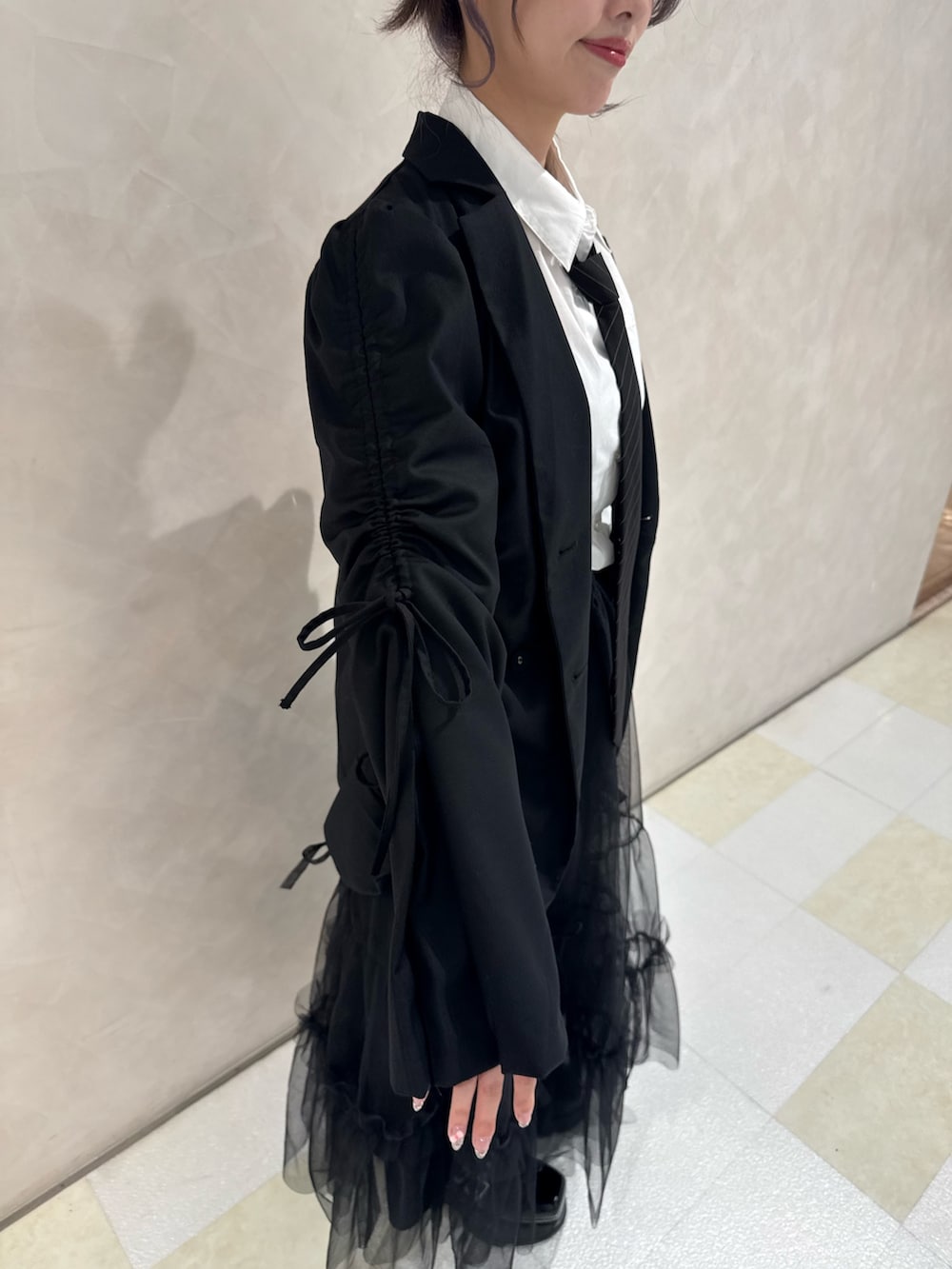 ブラック系のテーラードジャケット、ホワイト系のシャツ/ブラウス、ブラック系のネクタイを着用したレディースの秋コーディネートの5枚目の写真