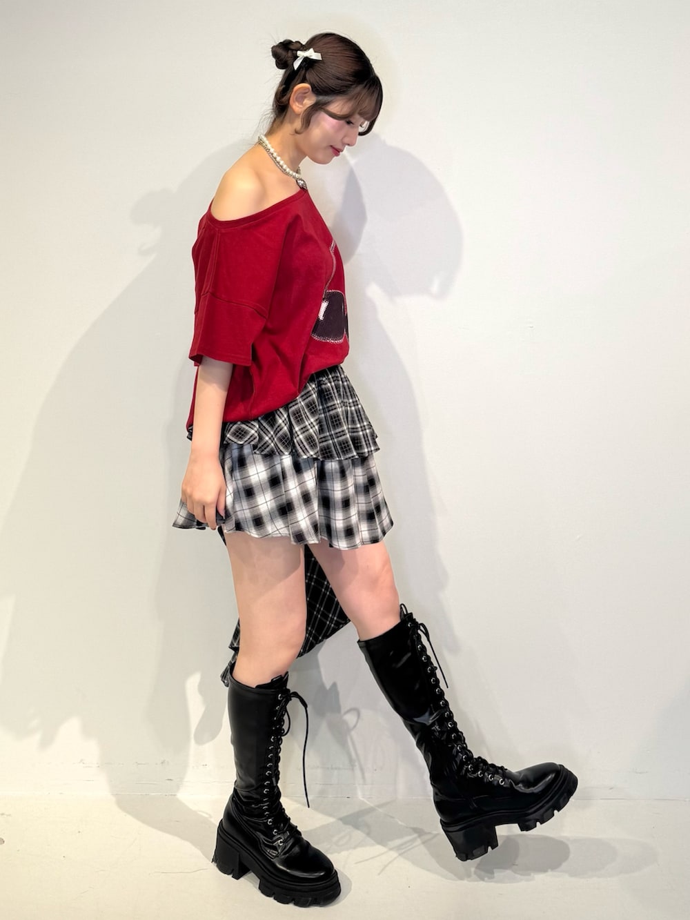 レッド系のTシャツ/カットソー、ブラック系のスカート、ブラック系のブーツを着用したレディースの春コーディネートの3枚目の写真