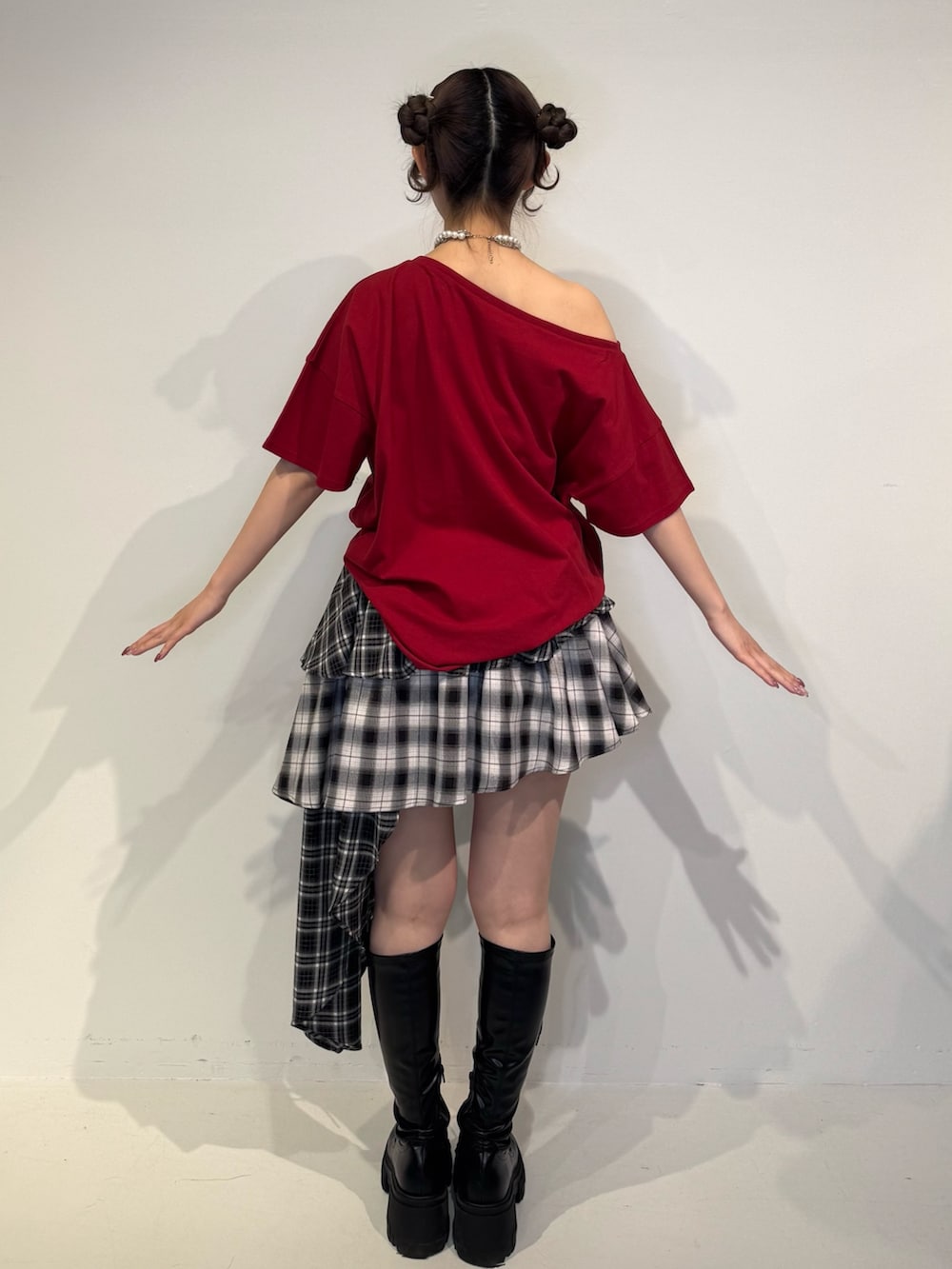 レッド系のTシャツ/カットソー、ブラック系のスカート、ブラック系のブーツを着用したレディースの春コーディネートの4枚目の写真