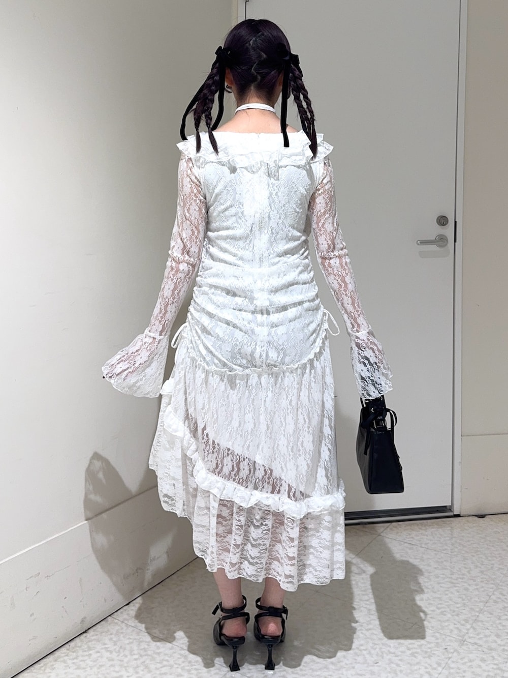 ホワイト系のワンピース、ブラック系のハンドバッグ、ブラック系のパンプスを着用したレディースの冬コーディネートの3枚目の写真