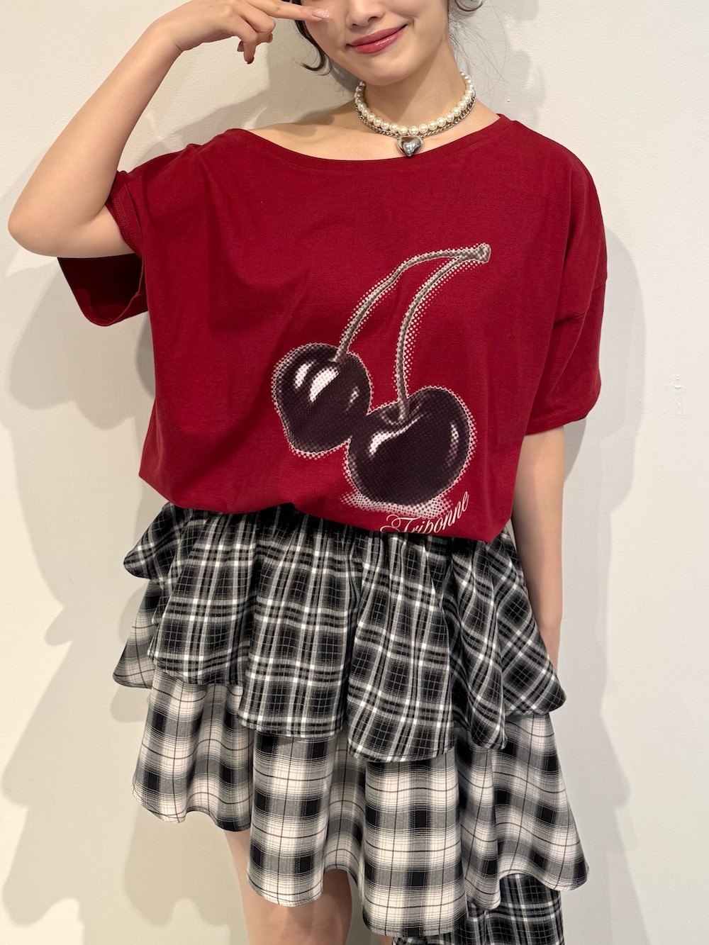 レッド系のTシャツ/カットソー、ブラック系のスカート、ブラック系のブーツを着用したレディースの春コーディネートの6枚目の写真