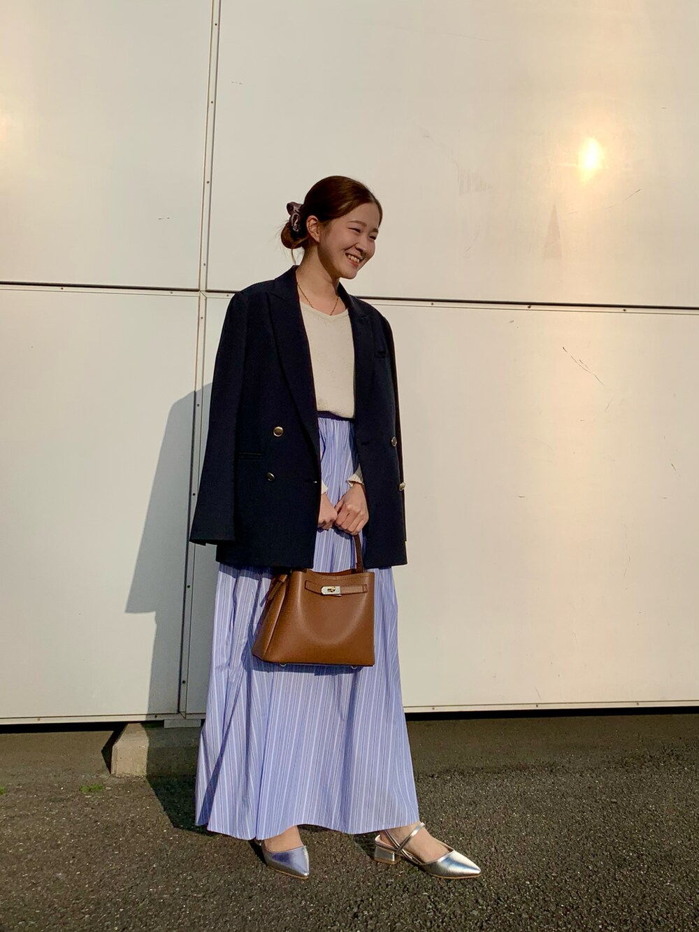 ホワイト系のニット/セーター、ブラウン系のハンドバッグ、ブルー系のスカートを着用したレディースの春コーディネートの3枚目の写真