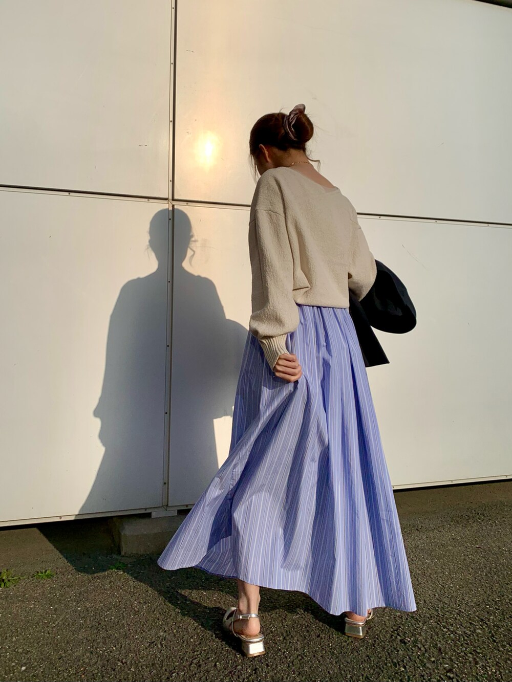 ホワイト系のニット/セーター、ブラウン系のハンドバッグ、ブルー系のスカートを着用したレディースの春コーディネートの2枚目の写真