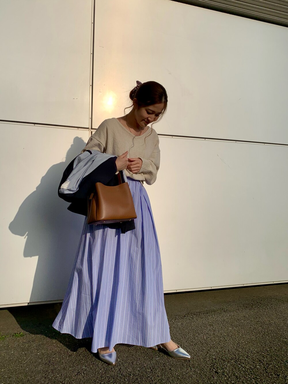 ホワイト系のニット/セーター、ブラウン系のハンドバッグ、ブルー系のスカートを着用したレディースの春コーディネートの5枚目の写真
