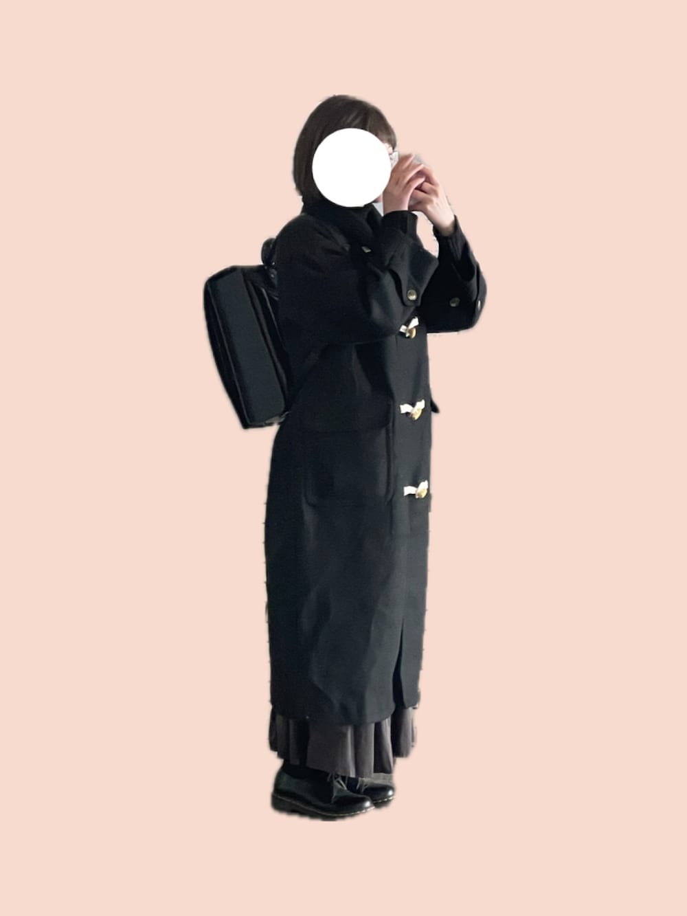 ブラック系のダッフルコート、ブラウン系のスカート、ブラック系のブーツを着用したレディースの冬コーディネートの2枚目の写真