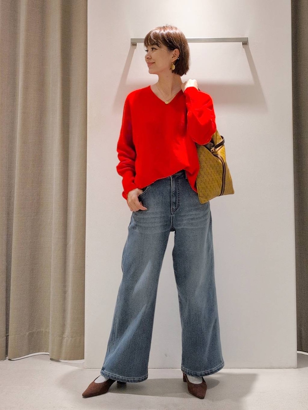 ブルー系のデニムパンツ、ブラウン系のパンプス、イエロー系のショルダーバッグを着用したレディースの秋コーディネートの2枚目の写真