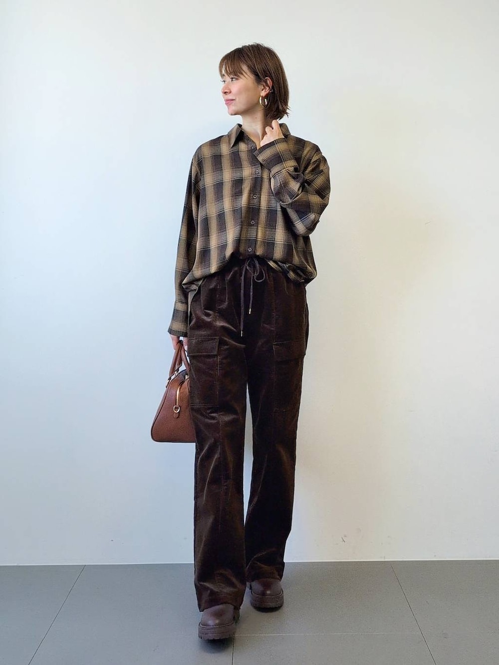 ブラウン系のブーツ、ブラウン系のボストンバッグ、ブラウン系のシャツ/ブラウスを着用したレディースの冬コーディネートの2枚目の写真