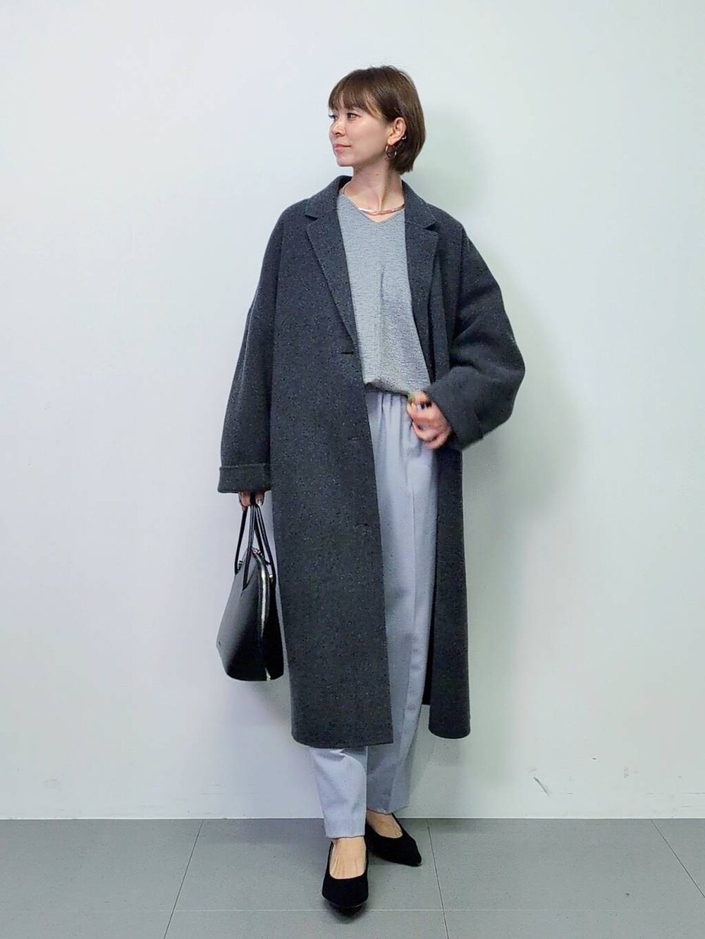 ブラック系のトートバッグ、グレー系のチェスターコート、ブラック系のパンプスを着用したレディースの秋コーディネートの3枚目の写真