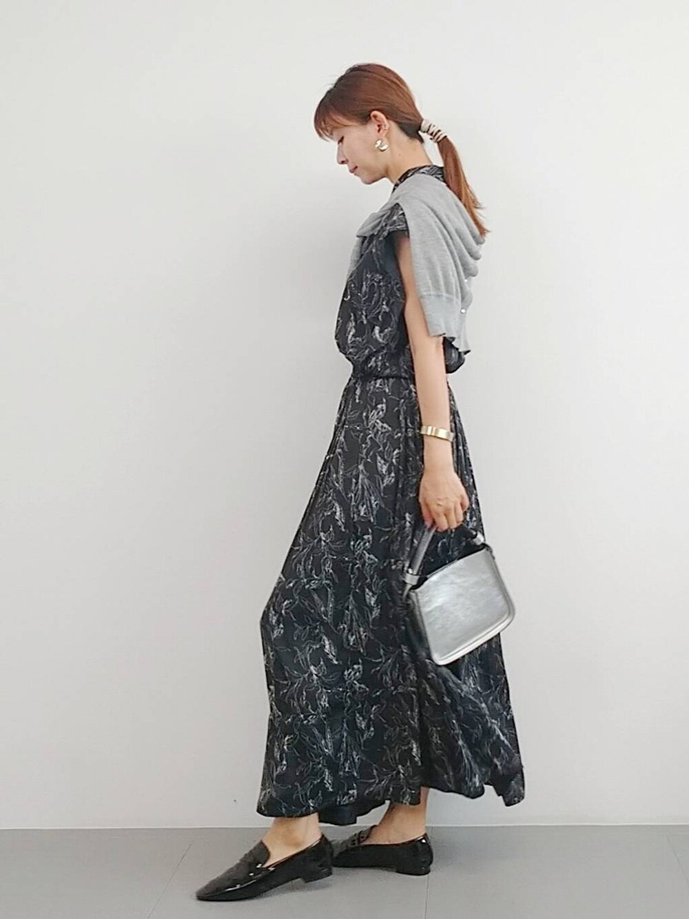 シルバー系のハンドバッグ、ブラック系のレインシューズ、グレー系のカーディガン/ボレロを着用したレディースの夏コーディネートの3枚目の写真