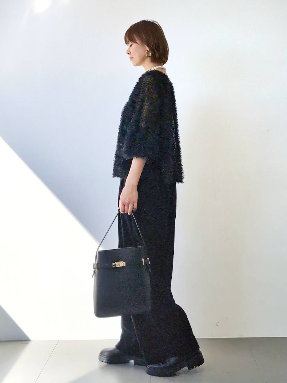 ブラック系のブーツ、ブラック系のハンドバッグ、ブラック系のキャミソールを着用したレディースの冬コーディネートの5枚目の写真