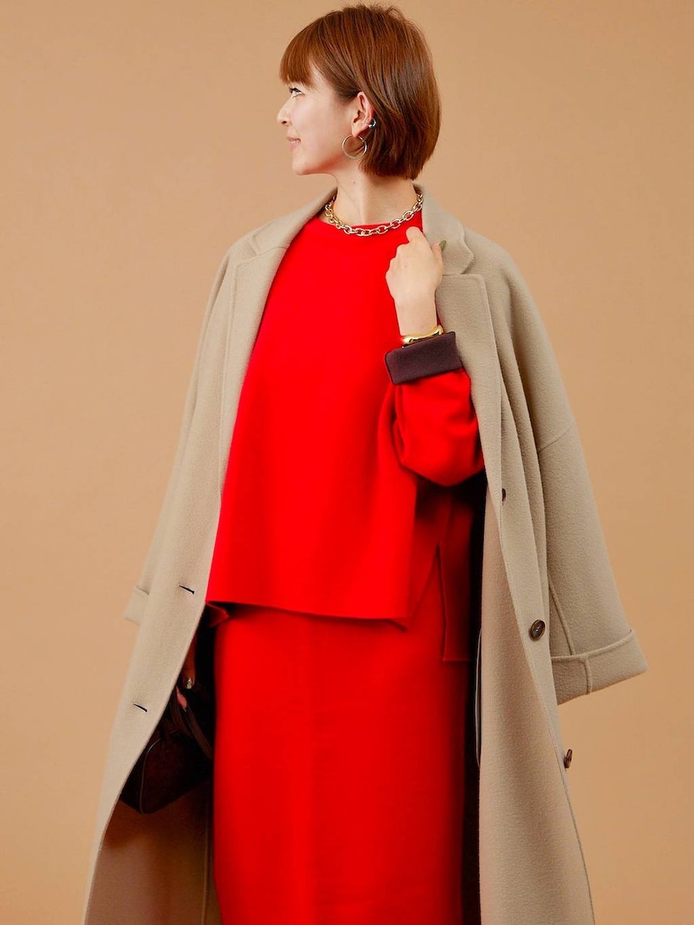 ベージュ系のチェスターコート、ブラウン系のショルダーバッグ、ブラウン系のブーツを着用したレディースの冬コーディネートの6枚目の写真