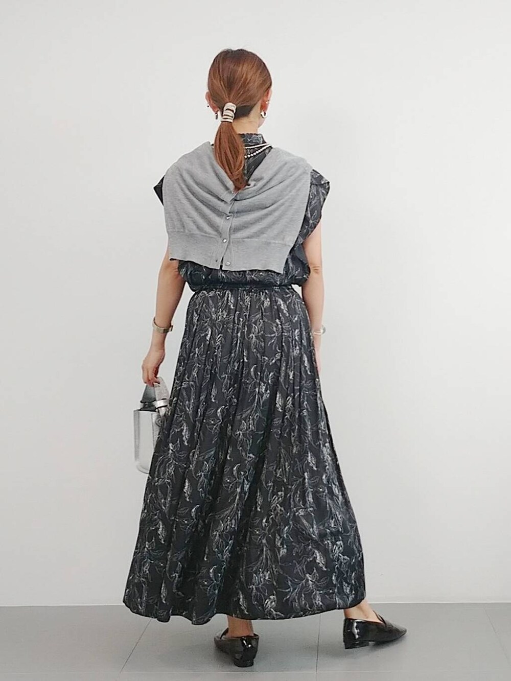 シルバー系のハンドバッグ、ブラック系のレインシューズ、グレー系のカーディガン/ボレロを着用したレディースの夏コーディネートの5枚目の写真