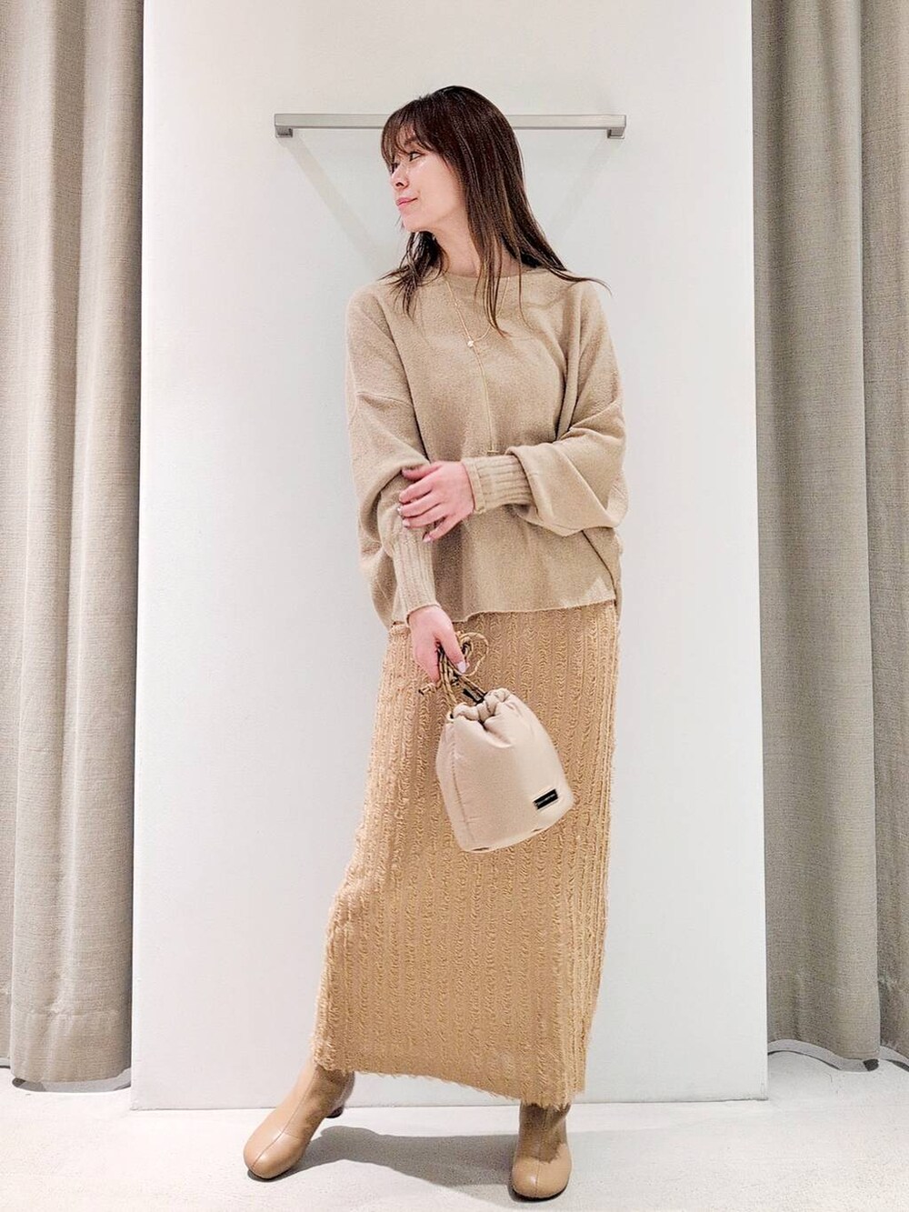 ベージュ系のブーツ、ベージュ系のショルダーバッグ、ベージュ系のニット/セーターを着用したレディースの冬コーディネートの2枚目の写真