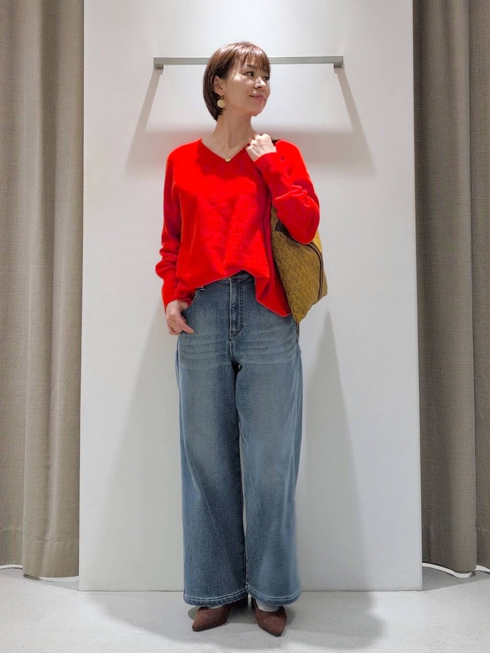 ブルー系のデニムパンツ、ブラウン系のパンプス、イエロー系のショルダーバッグを着用したレディースの秋コーディネートの6枚目の写真