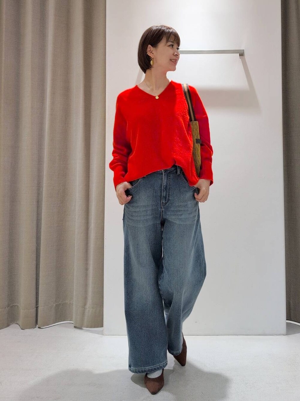 ブルー系のデニムパンツ、ブラウン系のパンプス、イエロー系のショルダーバッグを着用したレディースの秋コーディネートの5枚目の写真