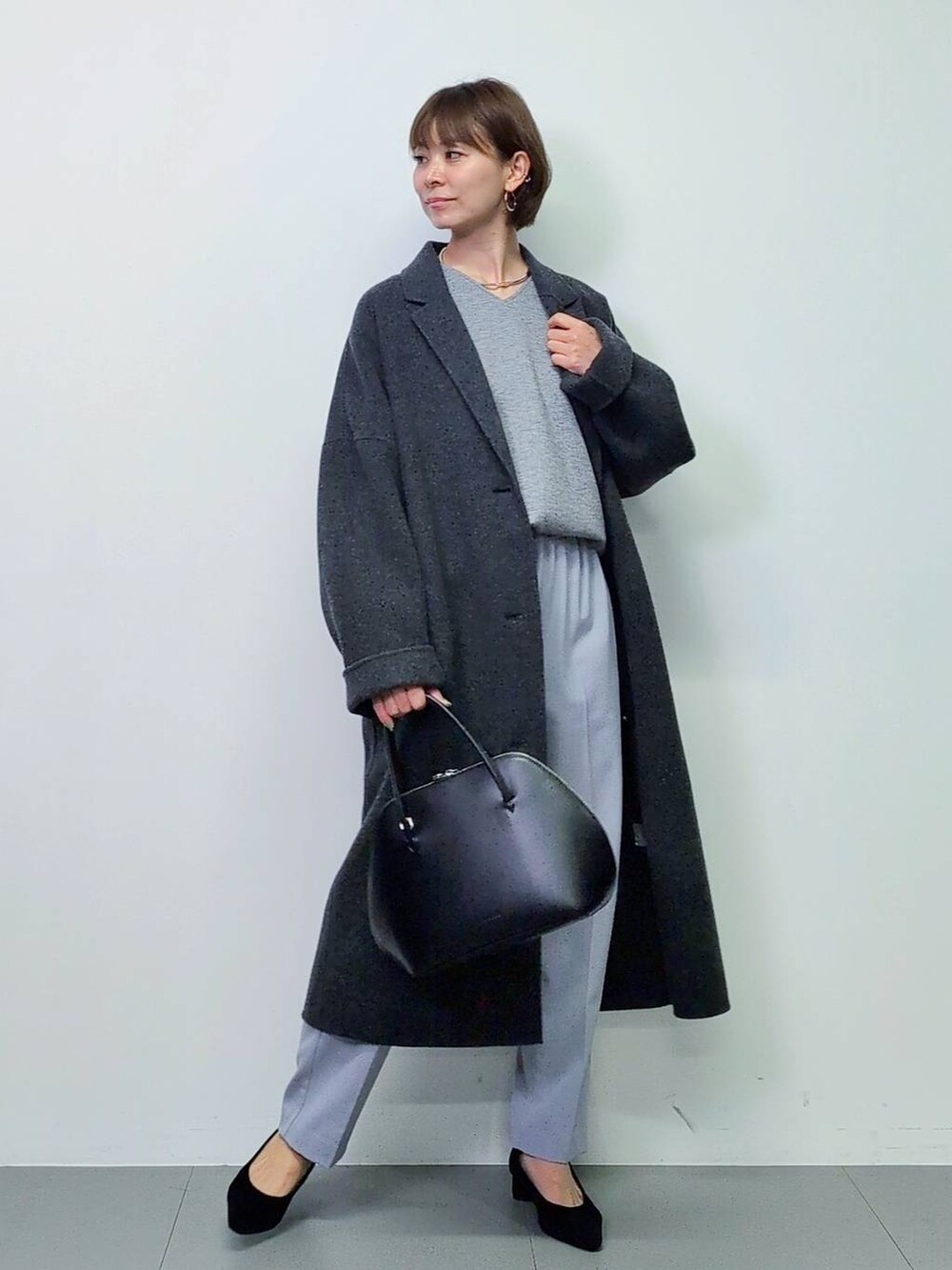 ブラック系のトートバッグ、グレー系のチェスターコート、ブラック系のパンプスを着用したレディースの秋コーディネートの4枚目の写真