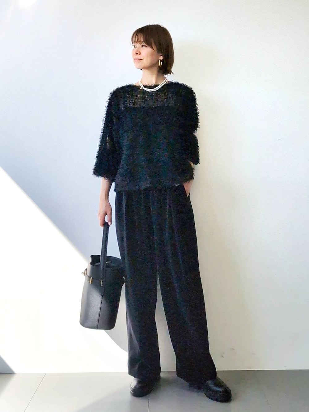 ブラック系のブーツ、ブラック系のハンドバッグ、ブラック系のキャミソールを着用したレディースの冬コーディネートの4枚目の写真