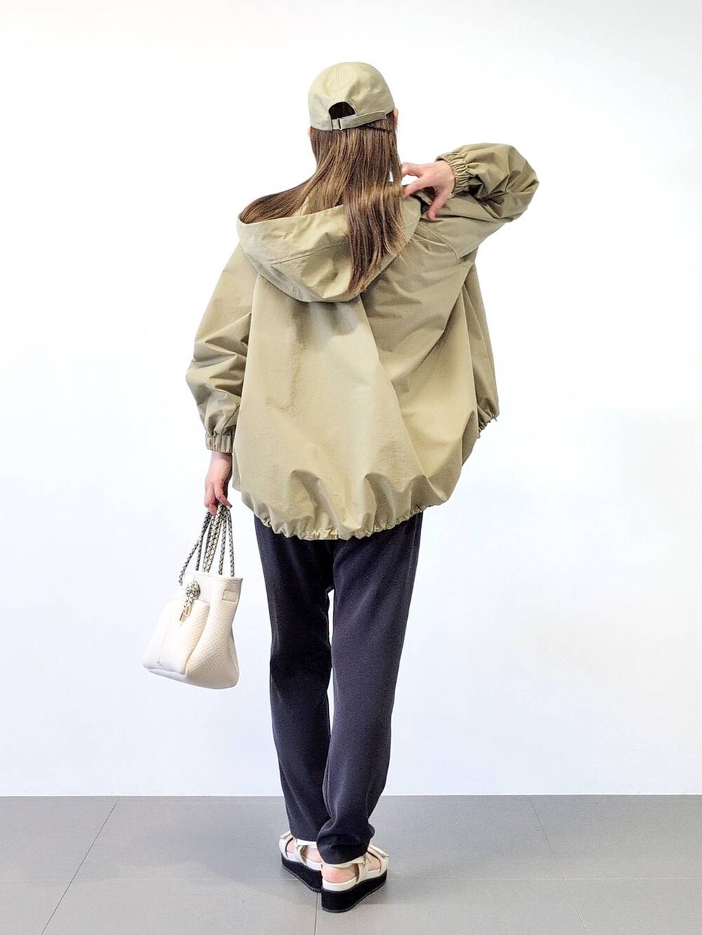 ホワイト系のトートバッグ、ブラック系のスラックス、ベージュ系のブルゾンを着用したレディースの冬コーディネートの6枚目の写真