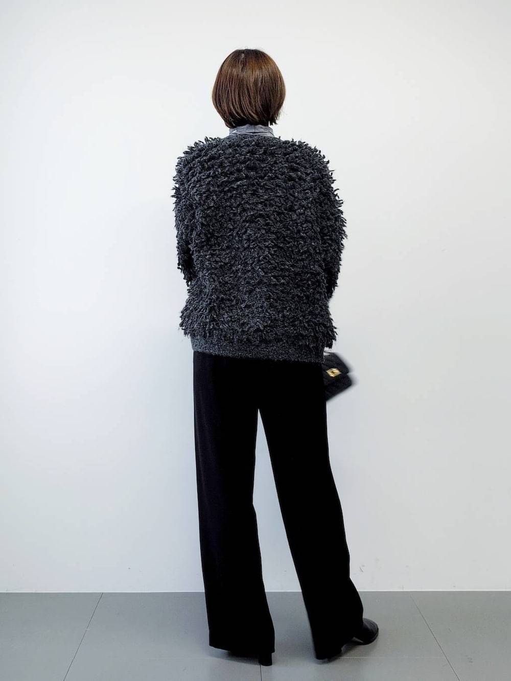 ブラック系のスラックス、ブラック系のブーツ、グレー系のカーディガン/ボレロを着用したレディースの秋コーディネートの7枚目の写真