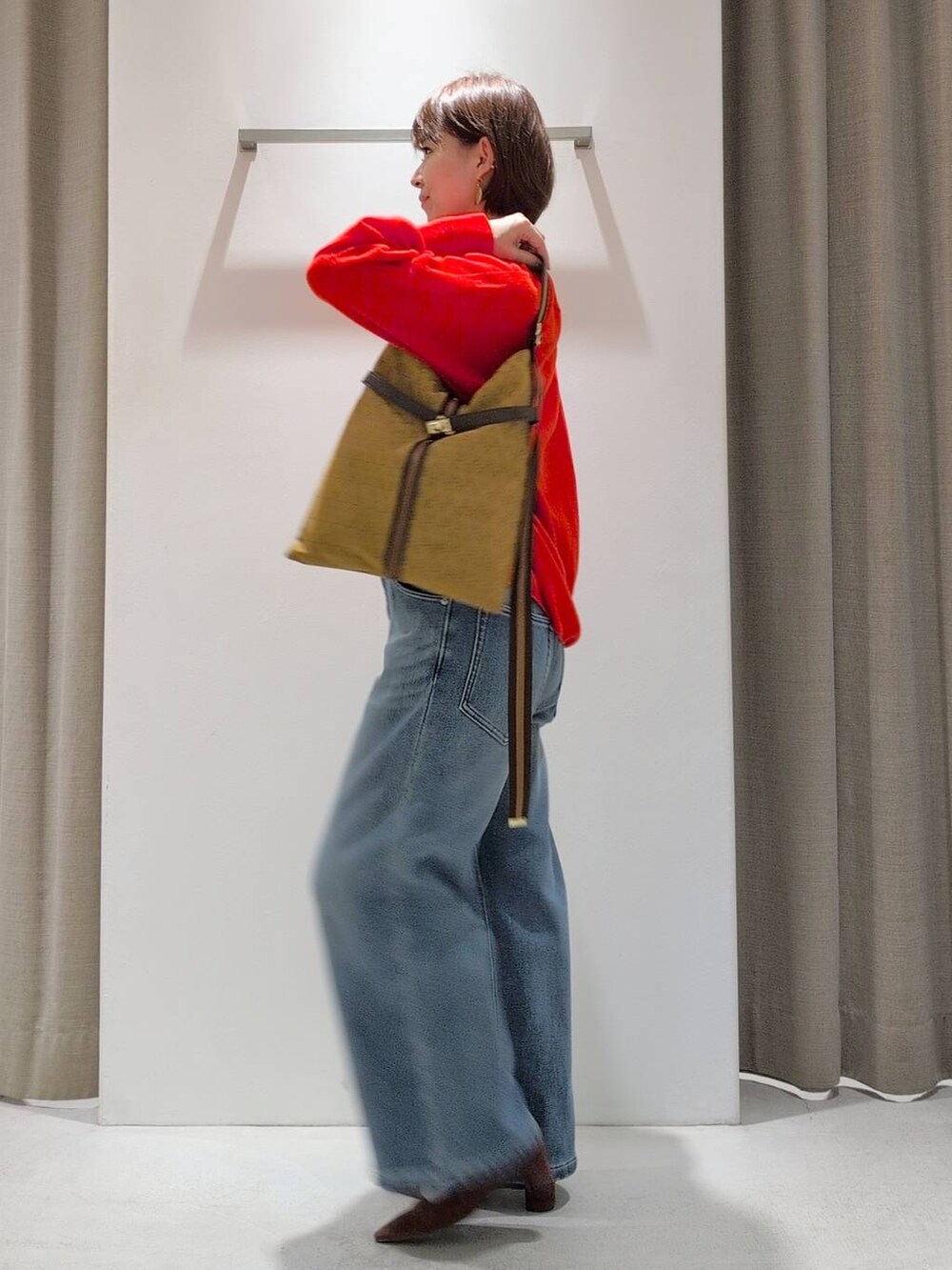 ブルー系のデニムパンツ、ブラウン系のパンプス、イエロー系のショルダーバッグを着用したレディースの秋コーディネートの7枚目の写真