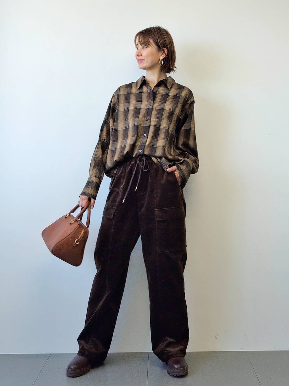 ブラウン系のブーツ、ブラウン系のボストンバッグ、ブラウン系のシャツ/ブラウスを着用したレディースの冬コーディネートの3枚目の写真