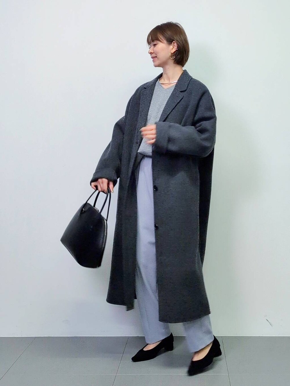 ブラック系のトートバッグ、グレー系のチェスターコート、ブラック系のパンプスを着用したレディースの秋コーディネートの5枚目の写真