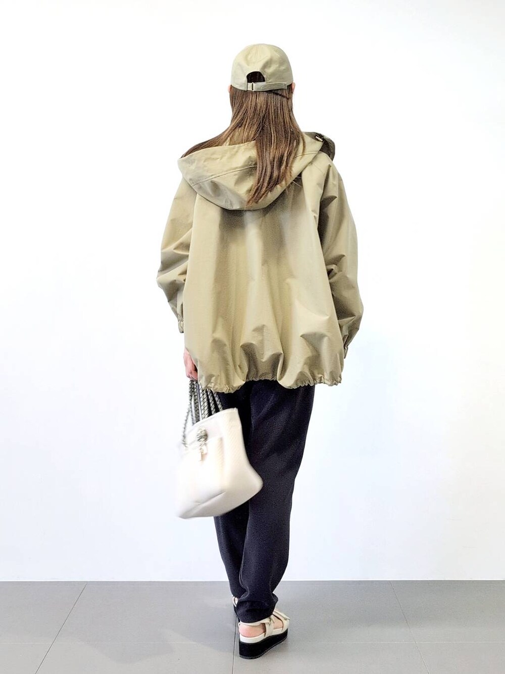 ホワイト系のトートバッグ、ブラック系のスラックス、ベージュ系のブルゾンを着用したレディースの冬コーディネートの5枚目の写真