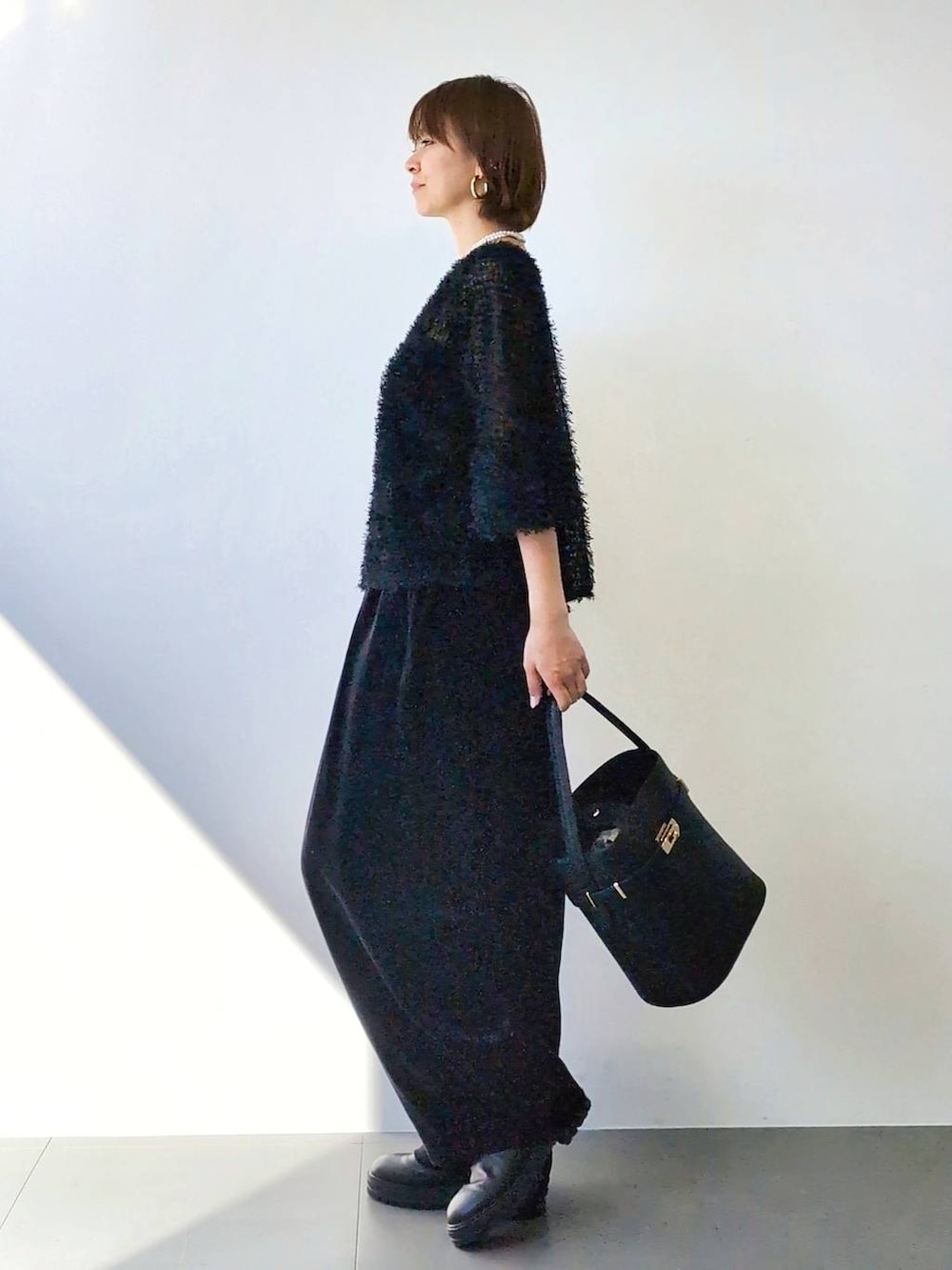 ブラック系のブーツ、ブラック系のハンドバッグ、ブラック系のキャミソールを着用したレディースの冬コーディネートの6枚目の写真