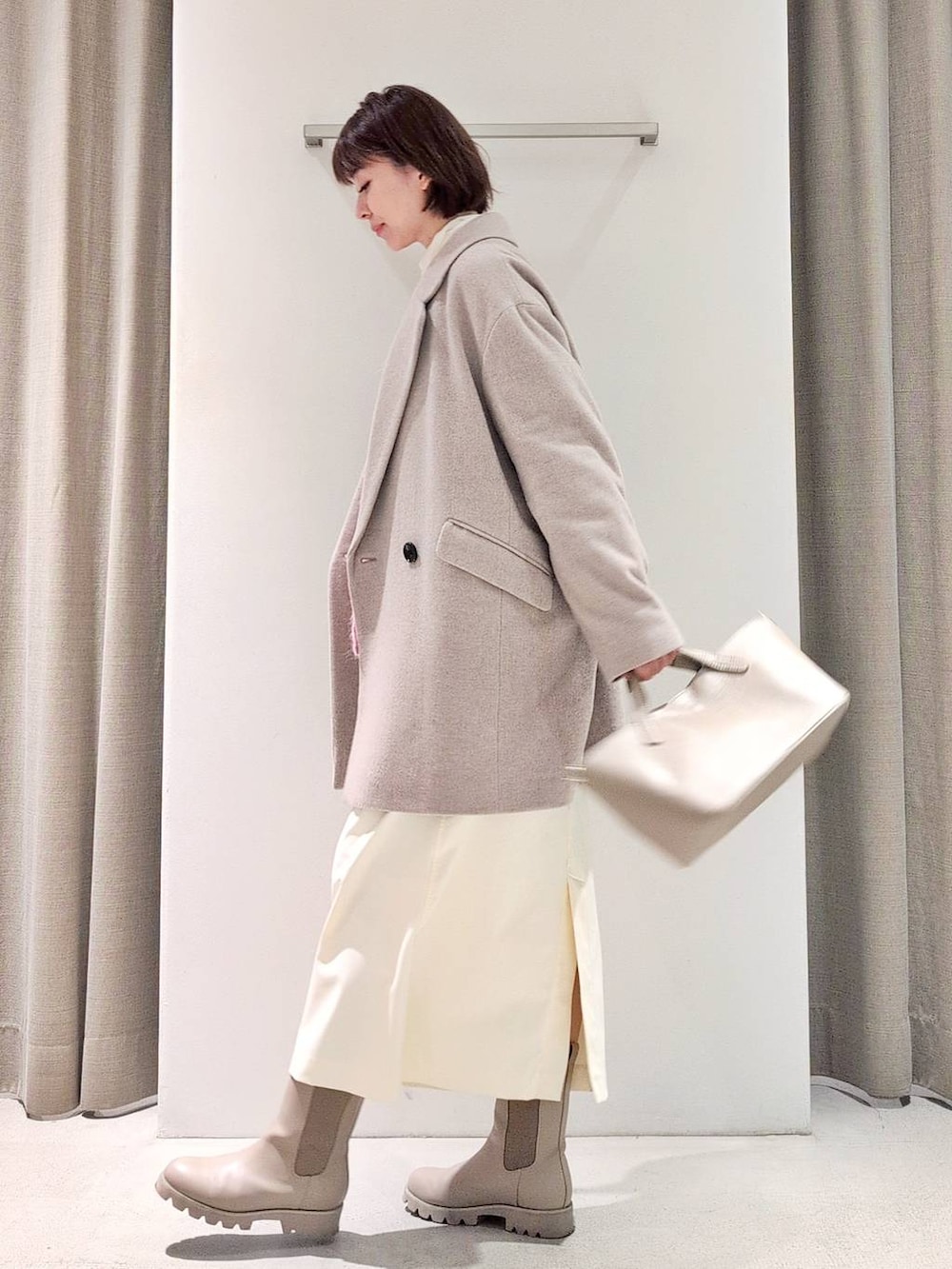 ホワイト系のTシャツ/カットソー、ベージュ系のピーコート、ホワイト系のスカートを着用したレディースの秋コーディネートの3枚目の写真