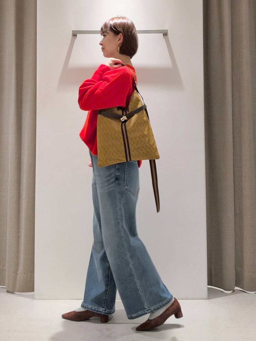 ブルー系のデニムパンツ、ブラウン系のパンプス、イエロー系のショルダーバッグを着用したレディースの秋コーディネートの8枚目の写真