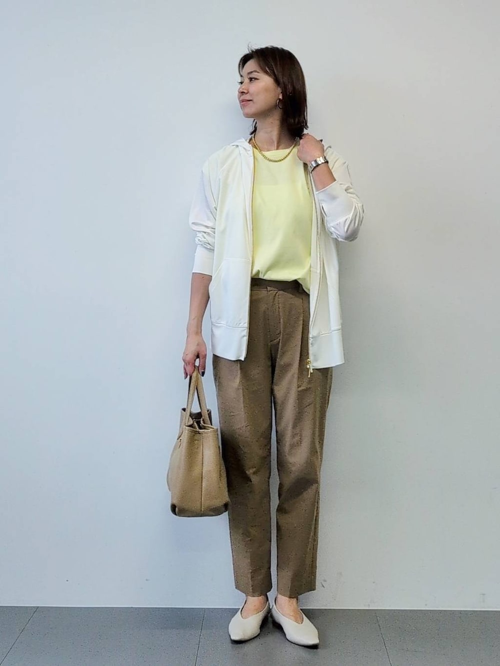 イエロー系のTシャツ/カットソー、ベージュ系のその他パンツ、ホワイト系のパーカーを着用したレディースの春コーディネートの2枚目の写真