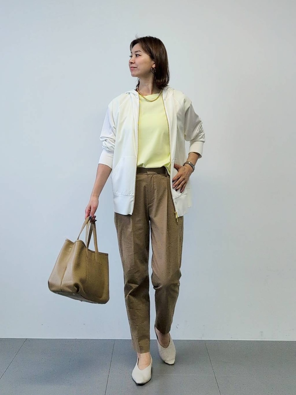 イエロー系のTシャツ/カットソー、ベージュ系のその他パンツ、ホワイト系のパーカーを着用したレディースの春コーディネートの4枚目の写真