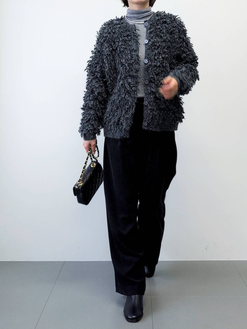 ブラック系のスラックス、ブラック系のブーツ、グレー系のカーディガン/ボレロを着用したレディースの秋コーディネートの8枚目の写真