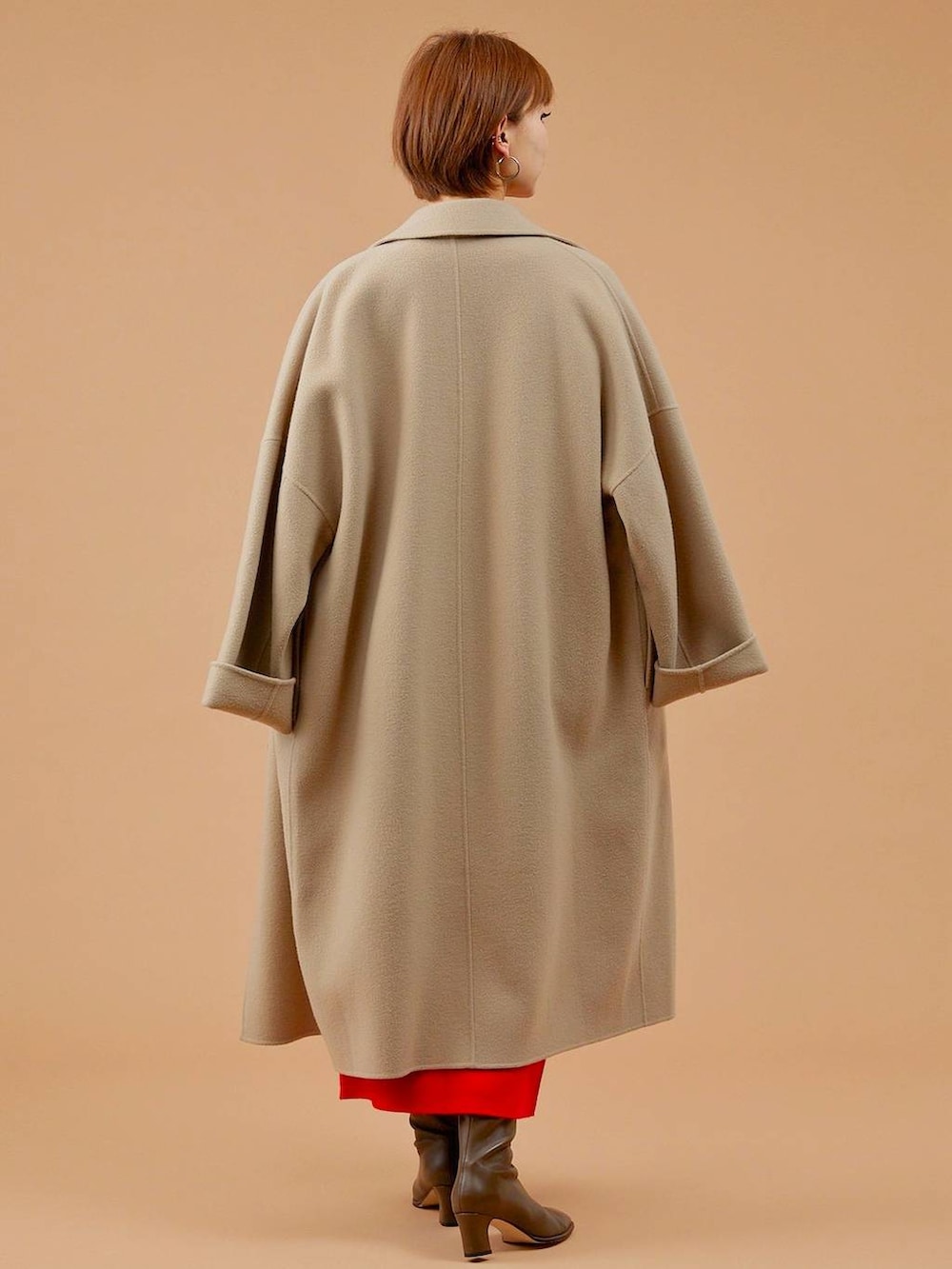 ベージュ系のチェスターコート、ブラウン系のショルダーバッグ、ブラウン系のブーツを着用したレディースの冬コーディネートの4枚目の写真