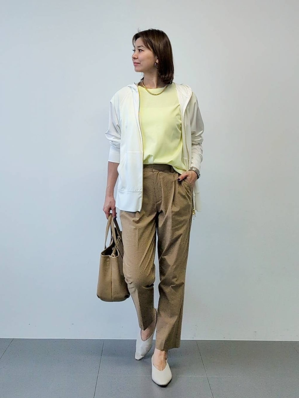 イエロー系のTシャツ/カットソー、ベージュ系のその他パンツ、ホワイト系のパーカーを着用したレディースの春コーディネートの3枚目の写真