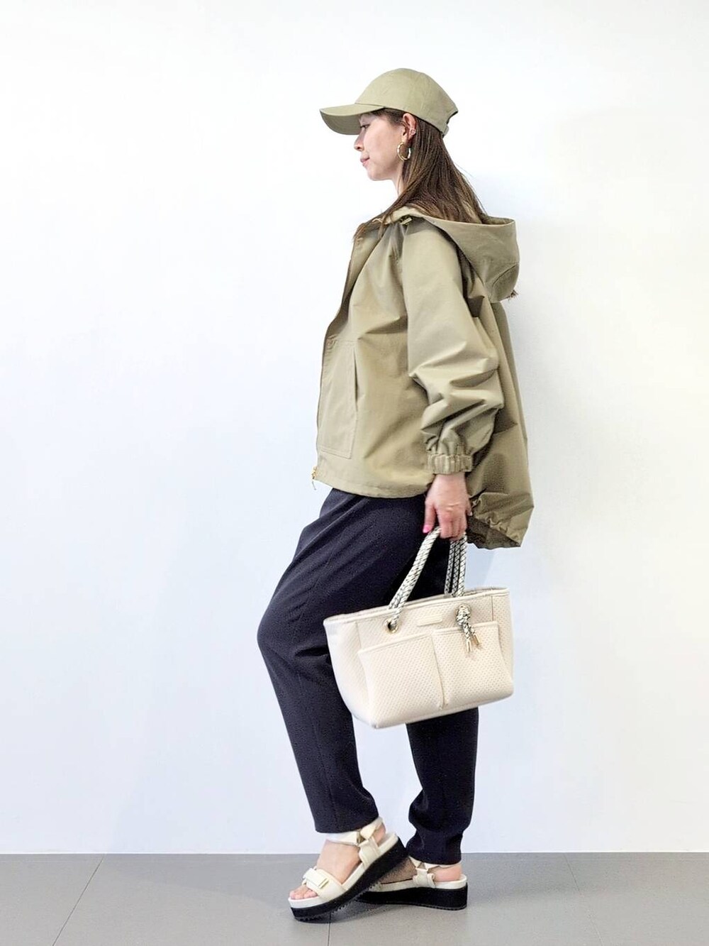 ホワイト系のトートバッグ、ブラック系のスラックス、ベージュ系のブルゾンを着用したレディースの冬コーディネートの4枚目の写真