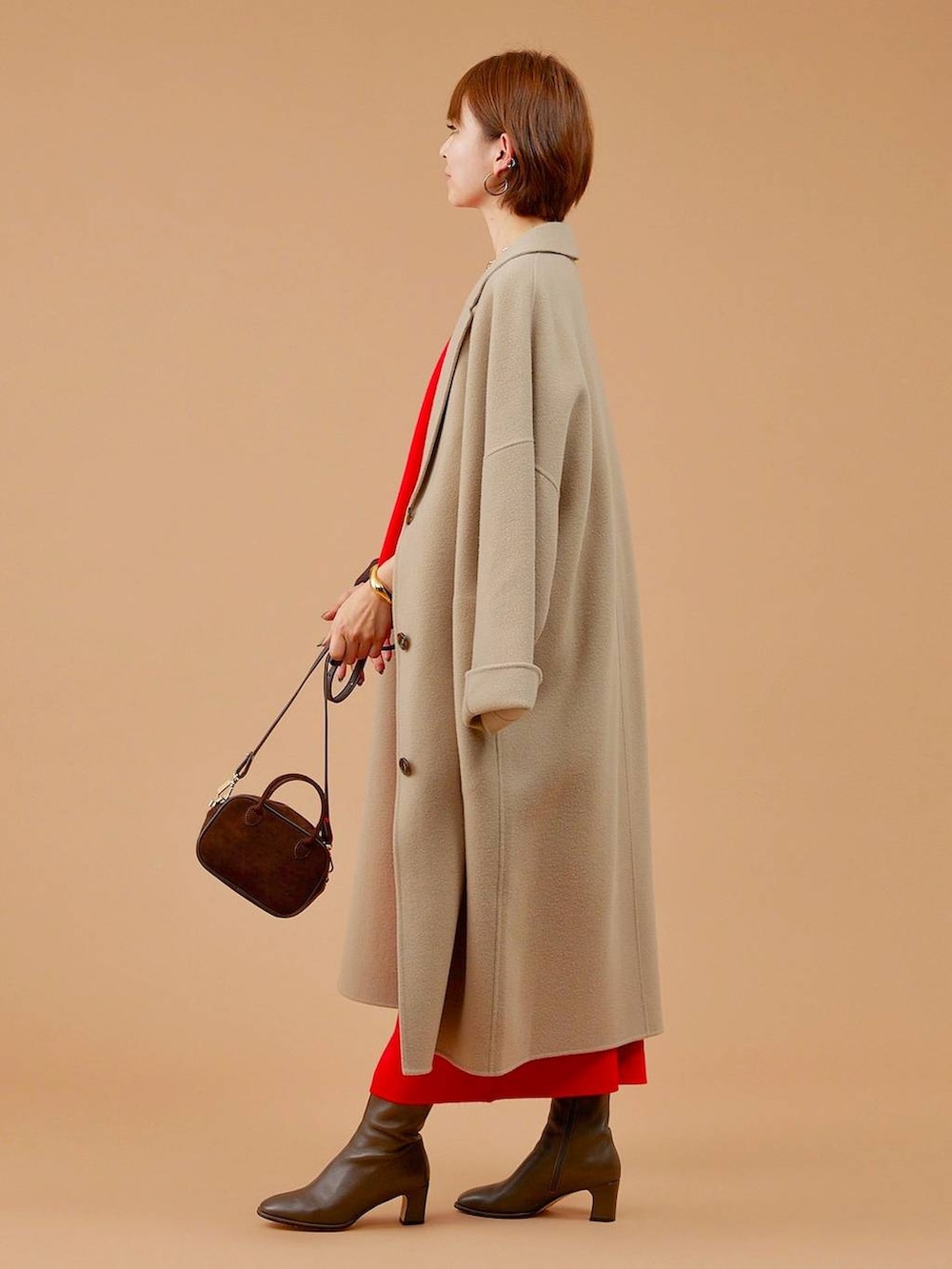 ベージュ系のチェスターコート、ブラウン系のショルダーバッグ、ブラウン系のブーツを着用したレディースの冬コーディネートの3枚目の写真