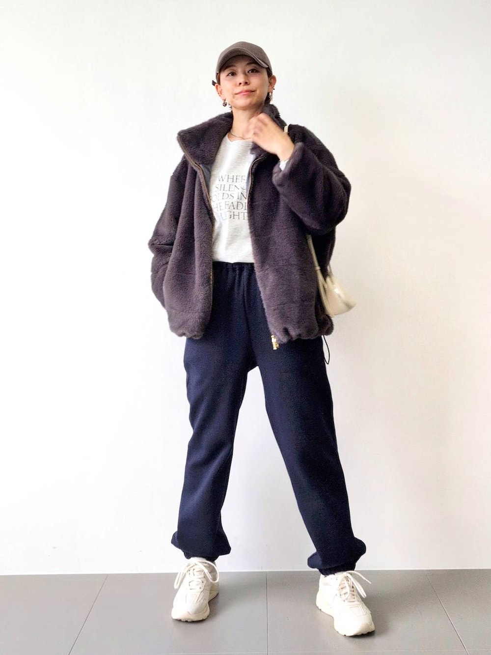 ホワイト系のショルダーバッグ、グレー系のブルゾン、ホワイト系のスニーカーを着用したレディースの秋コーディネートの2枚目の写真