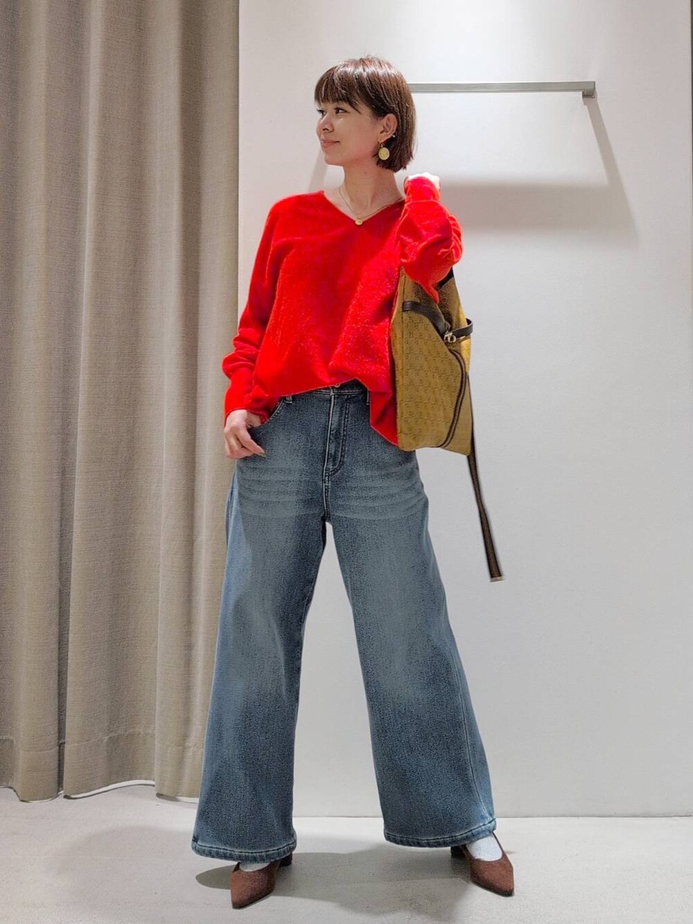 ブルー系のデニムパンツ、ブラウン系のパンプス、イエロー系のショルダーバッグを着用したレディースの秋コーディネートの4枚目の写真