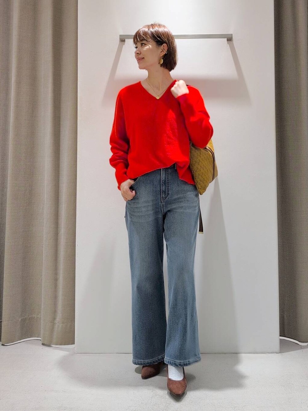 ブルー系のデニムパンツ、ブラウン系のパンプス、イエロー系のショルダーバッグを着用したレディースの秋コーディネートの3枚目の写真