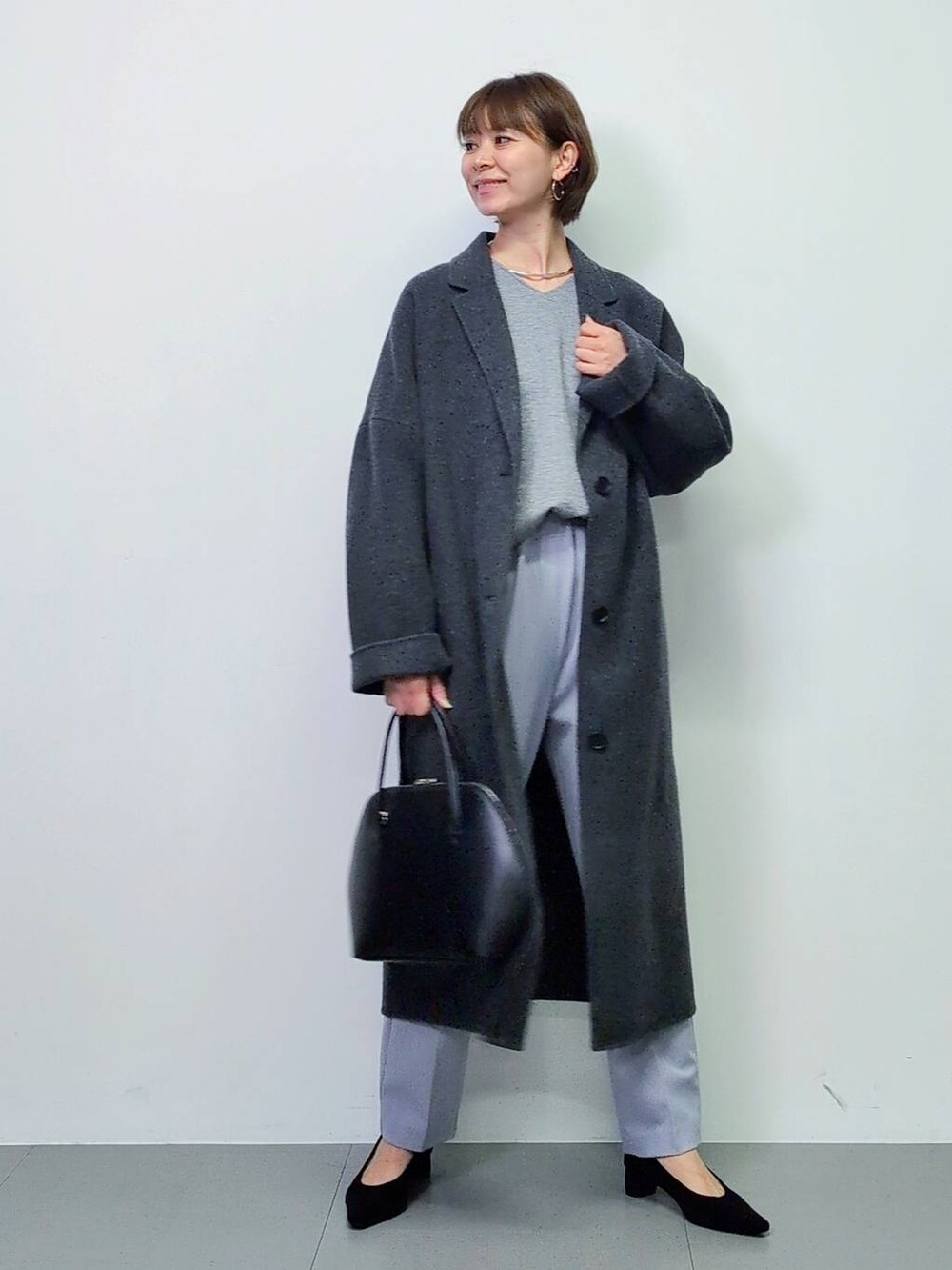 ブラック系のトートバッグ、グレー系のチェスターコート、ブラック系のパンプスを着用したレディースの秋コーディネートの2枚目の写真