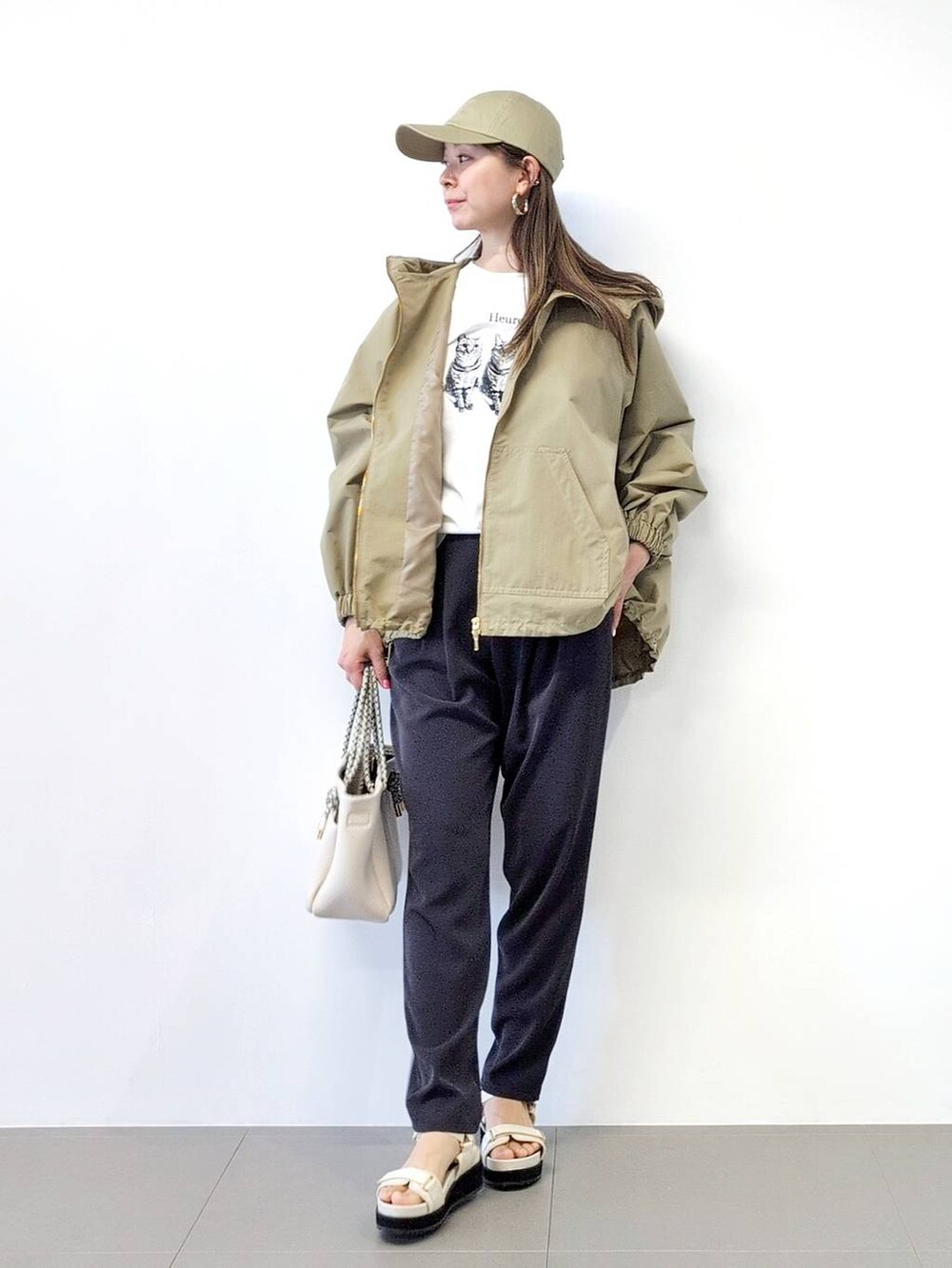 ホワイト系のトートバッグ、ブラック系のスラックス、ベージュ系のブルゾンを着用したレディースの冬コーディネートの2枚目の写真