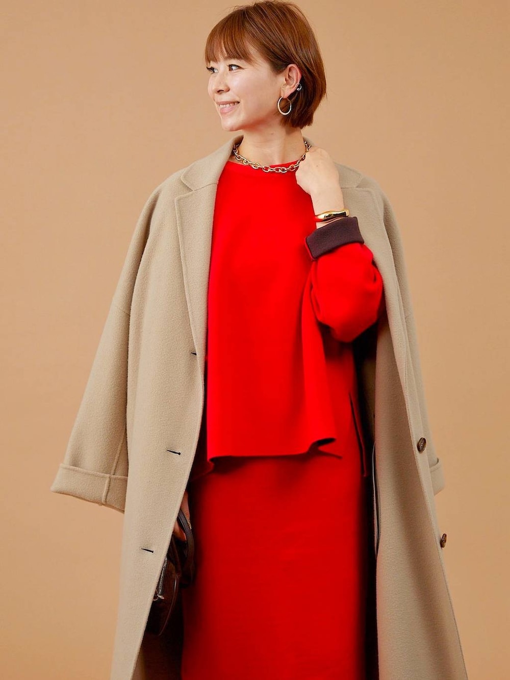 ベージュ系のチェスターコート、ブラウン系のショルダーバッグ、ブラウン系のブーツを着用したレディースの冬コーディネートの5枚目の写真