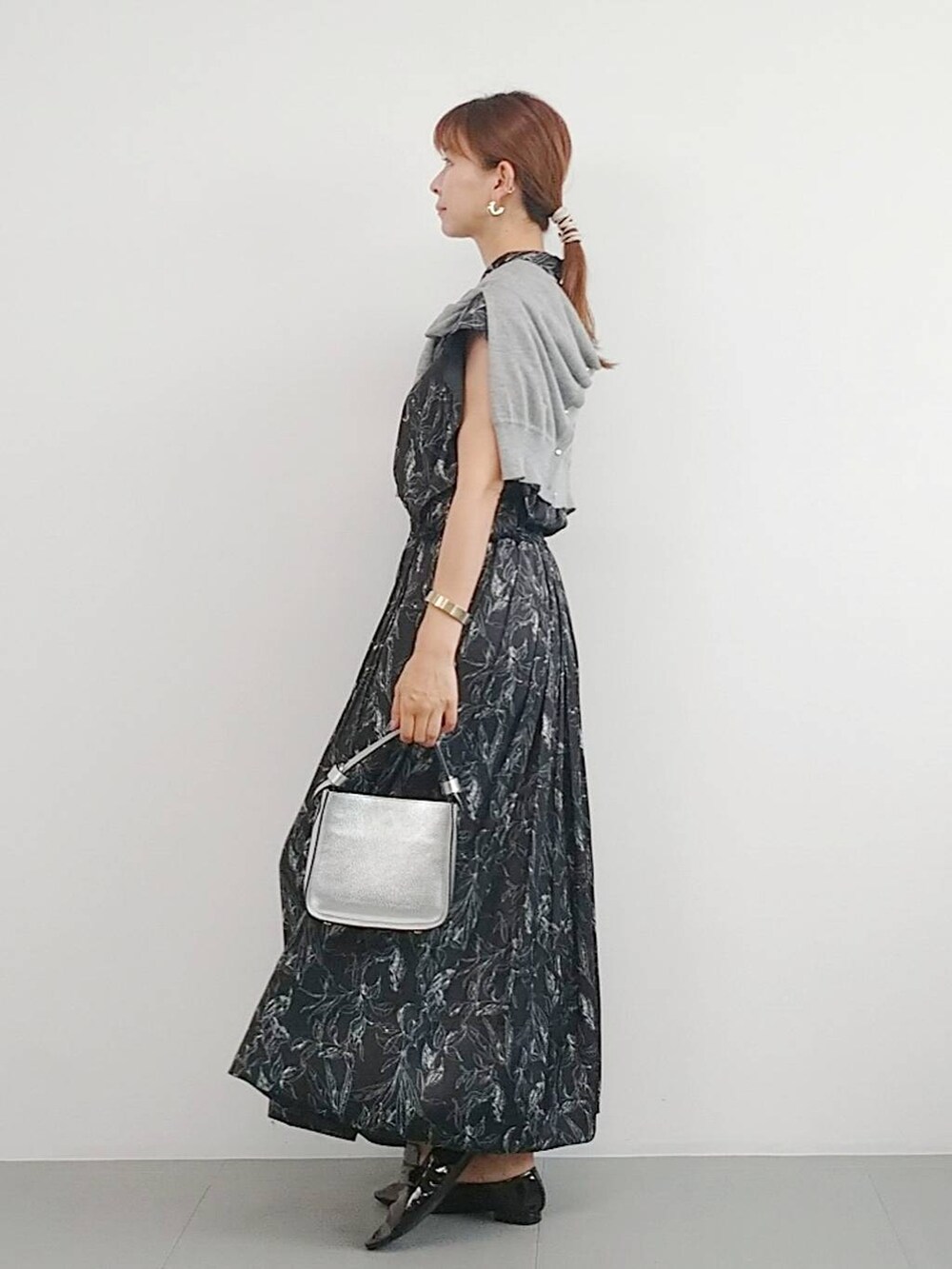 シルバー系のハンドバッグ、ブラック系のレインシューズ、グレー系のカーディガン/ボレロを着用したレディースの夏コーディネートの4枚目の写真