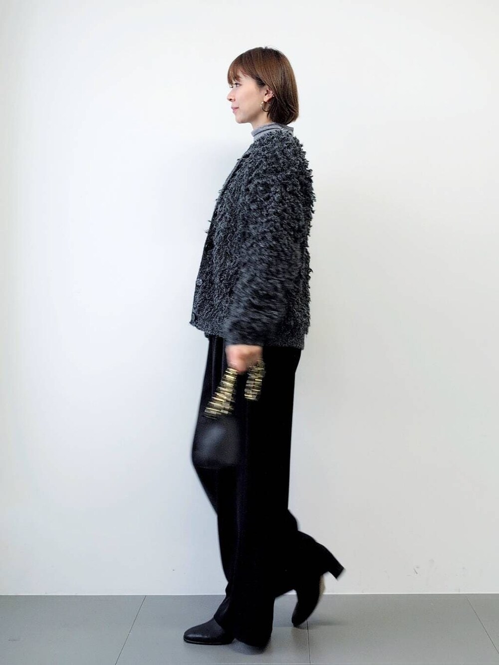 ブラック系のスラックス、ブラック系のブーツ、グレー系のカーディガン/ボレロを着用したレディースの秋コーディネートの6枚目の写真