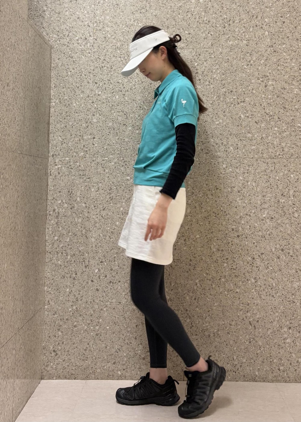 ホワイト系のスカート、ブルー系のポロシャツ、ホワイト系のサンバイザーを着用したレディースの春コーディネートの2枚目の写真