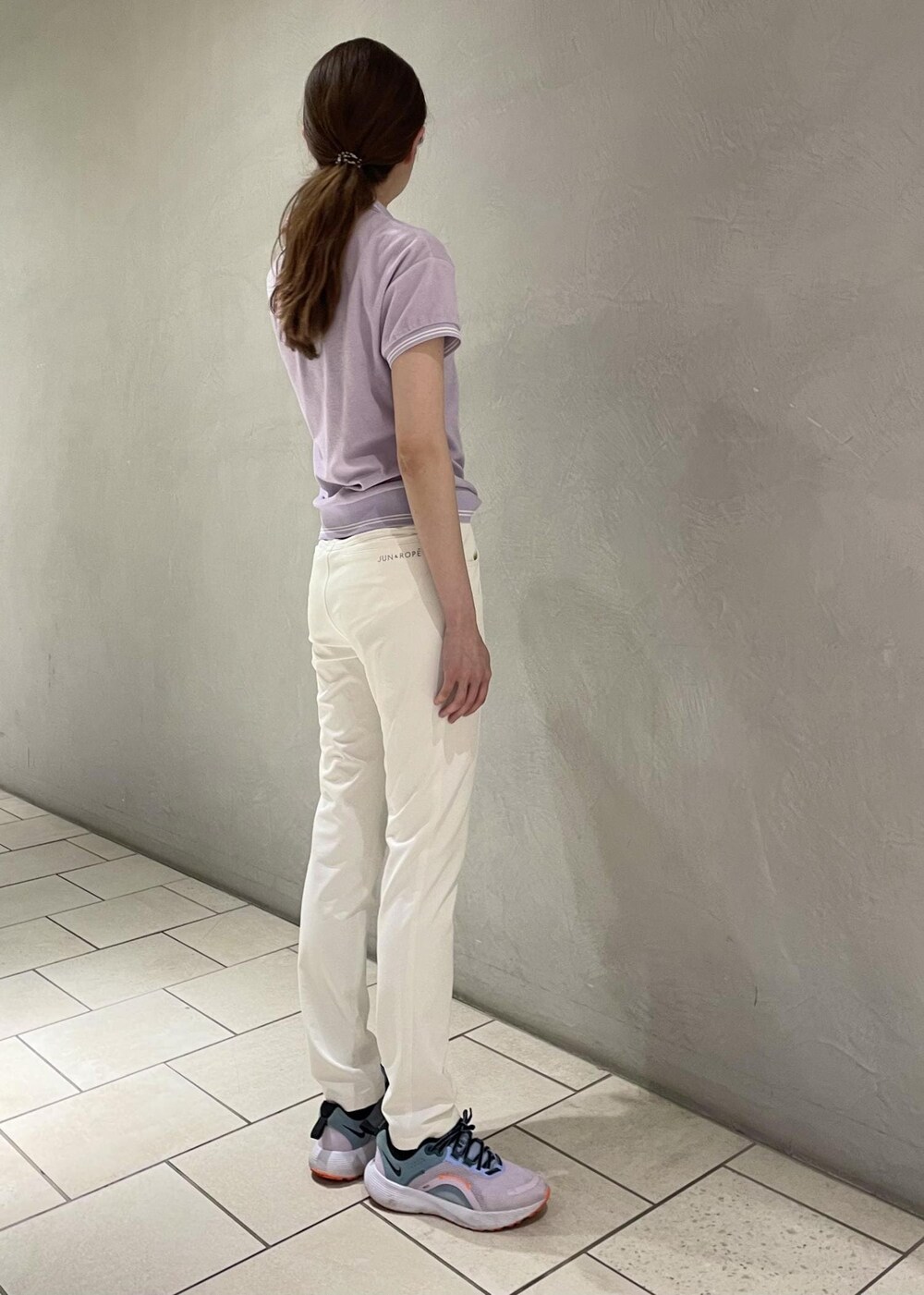 パープル系のポロシャツ、ホワイト系のその他パンツ、ブラック系のベルトを着用したレディースの春コーディネートの2枚目の写真