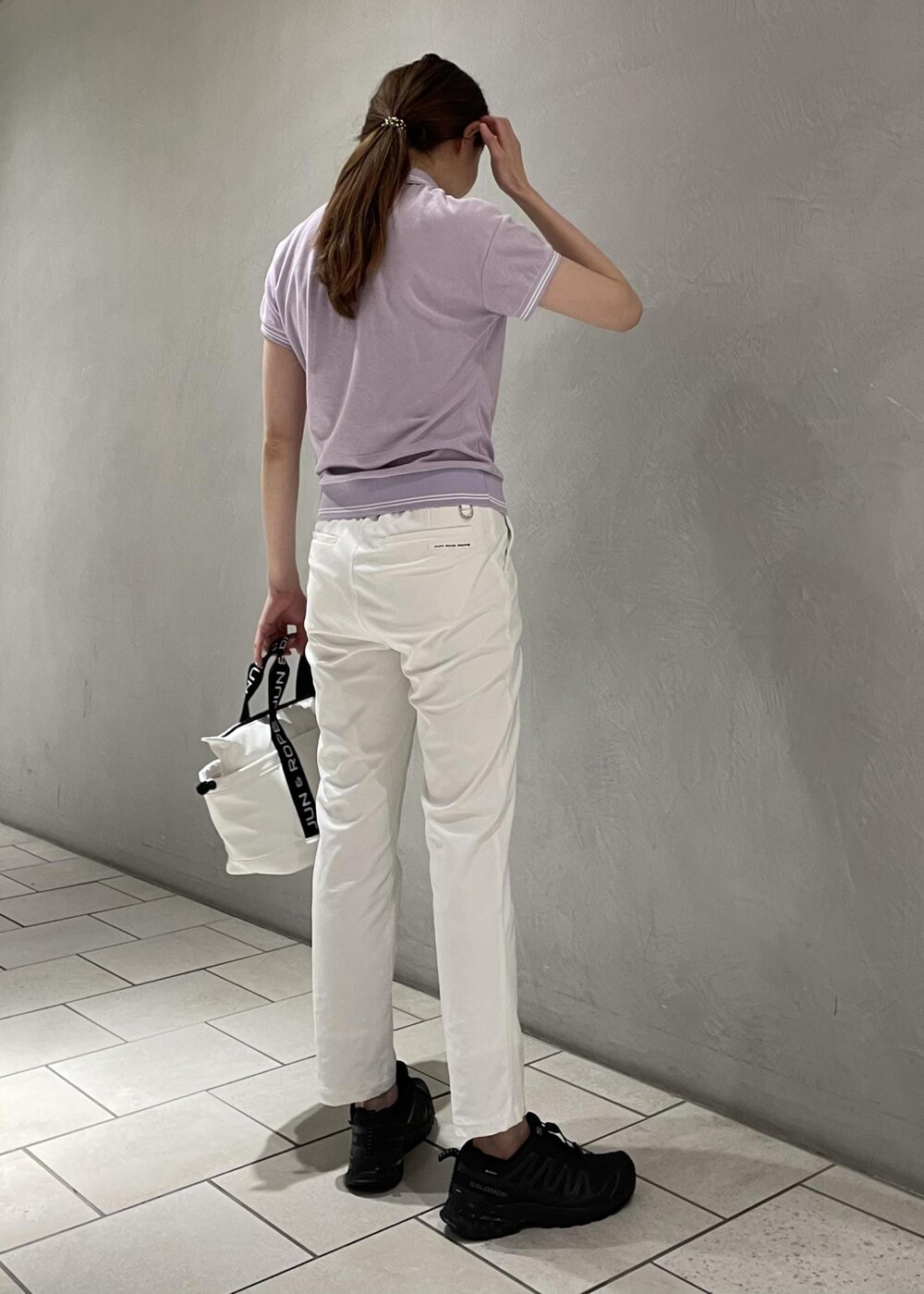 ホワイト系のハンドバッグ、ホワイト系のその他パンツ、パープル系のポロシャツを着用したレディースの春コーディネートの3枚目の写真