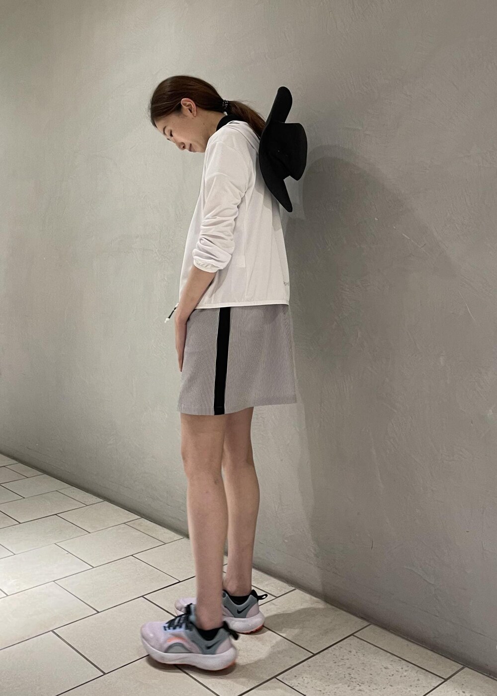 ブラック系のワンピース、ホワイト系のパーカー、ブラック系のハットを着用したレディースの春コーディネートの2枚目の写真