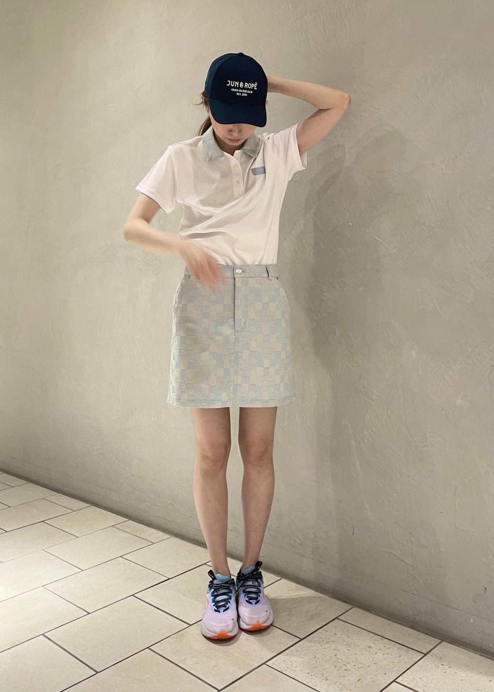ブルー系のポロシャツ、ブルー系のスカート、ブルー系のキャップを着用したレディースの夏コーディネートの2枚目の写真